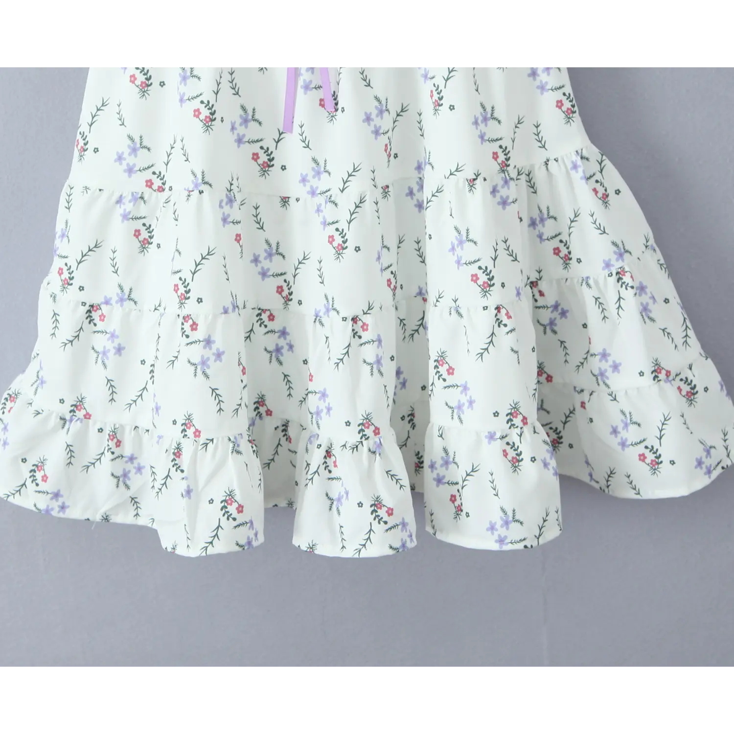 Full view tiered ruffle skirt of white floral mini dress, flowy layered hem with small flower print