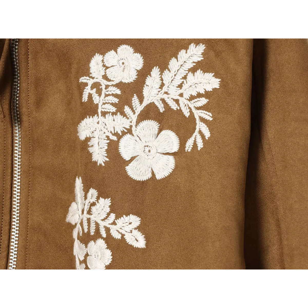 Macro closeup of white floral and leaf embroidery on brown faux suede jacket fabric