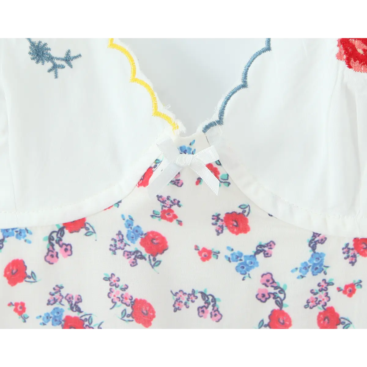 Close-up of the tiny white satin bow detail at the center front of the embroidered cups