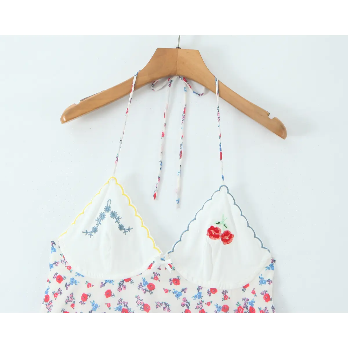  Close-up of the embroidered cherry and floral details on the scalloped cup neckline of the slip dress