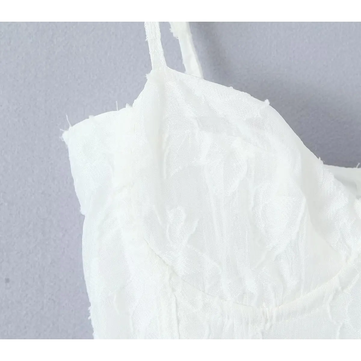 Close-up of the molded bust cup and textured floral jacquard fabric on the white dress