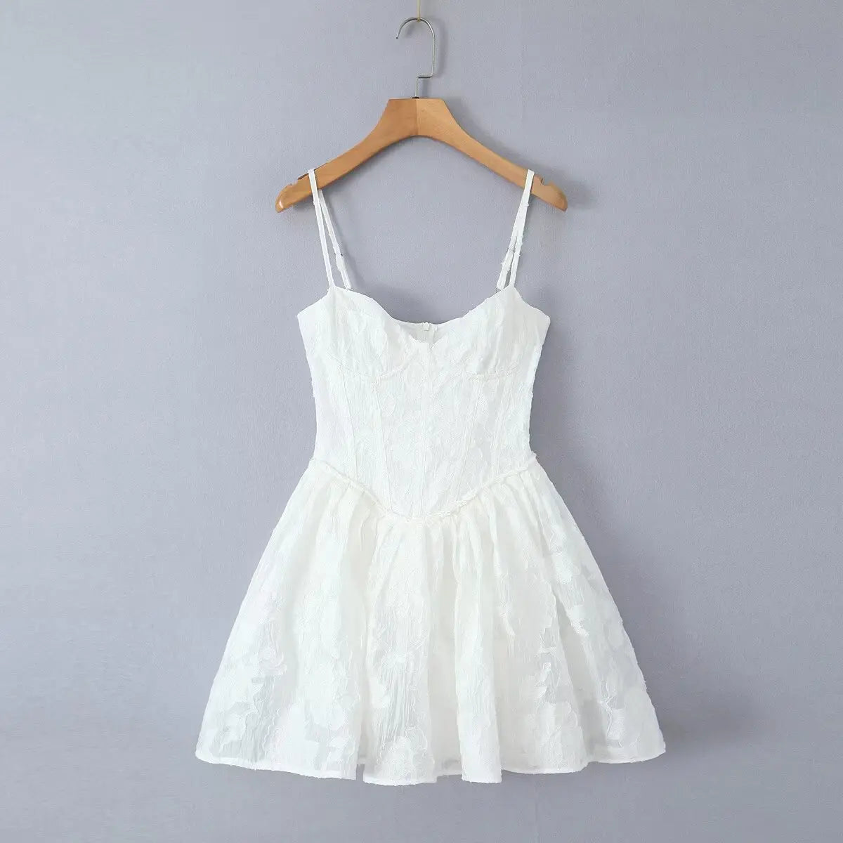 Full front view of white corset-style spaghetti strap mini dress on wooden hanger
