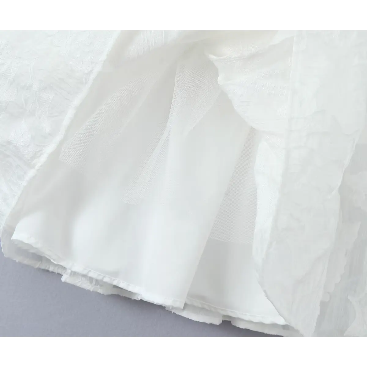 Close-up of the tulle and smooth lining inside the white jacquard dress skirt