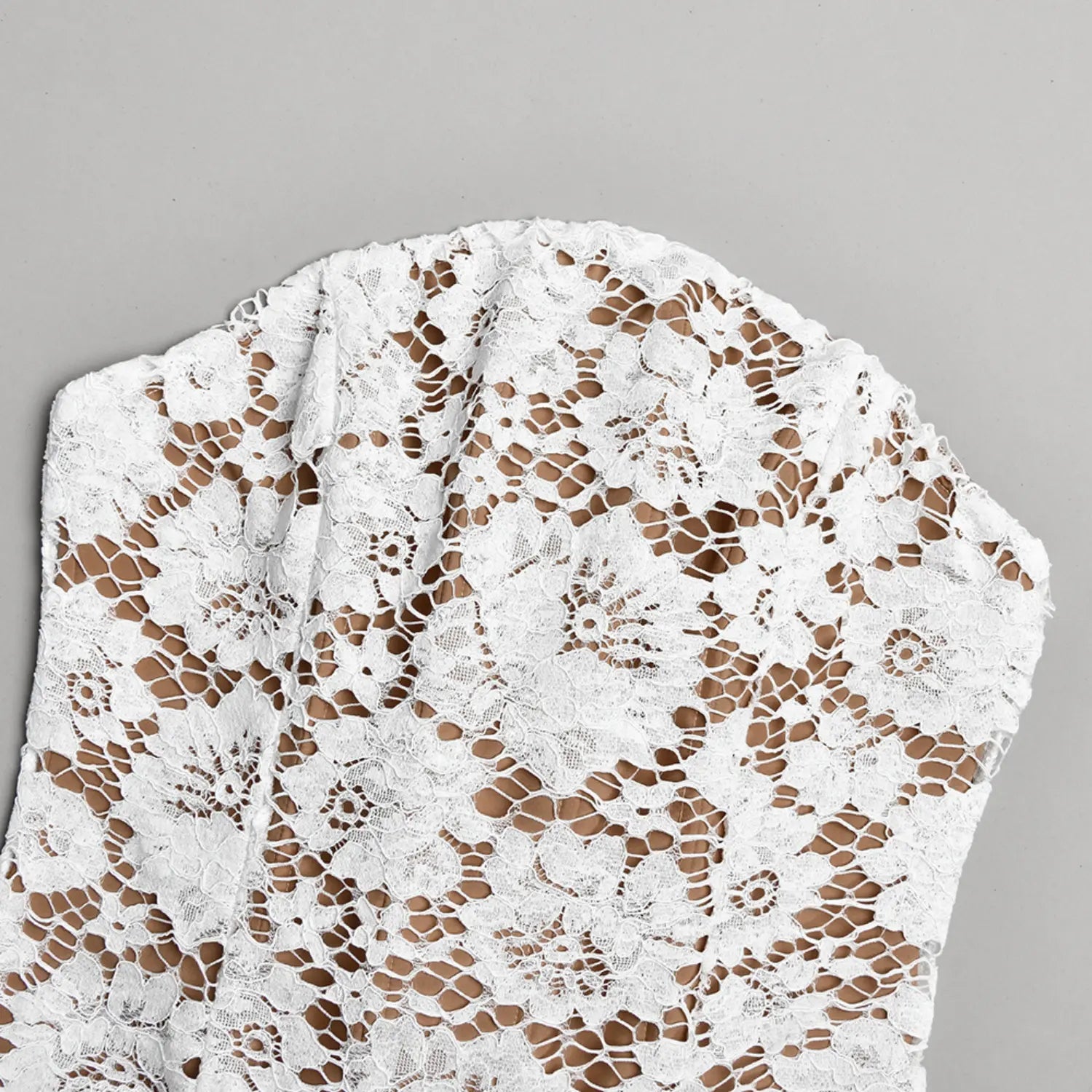 Close‑up shot inner boning and nude lining construction of white strapless lace dress bodice