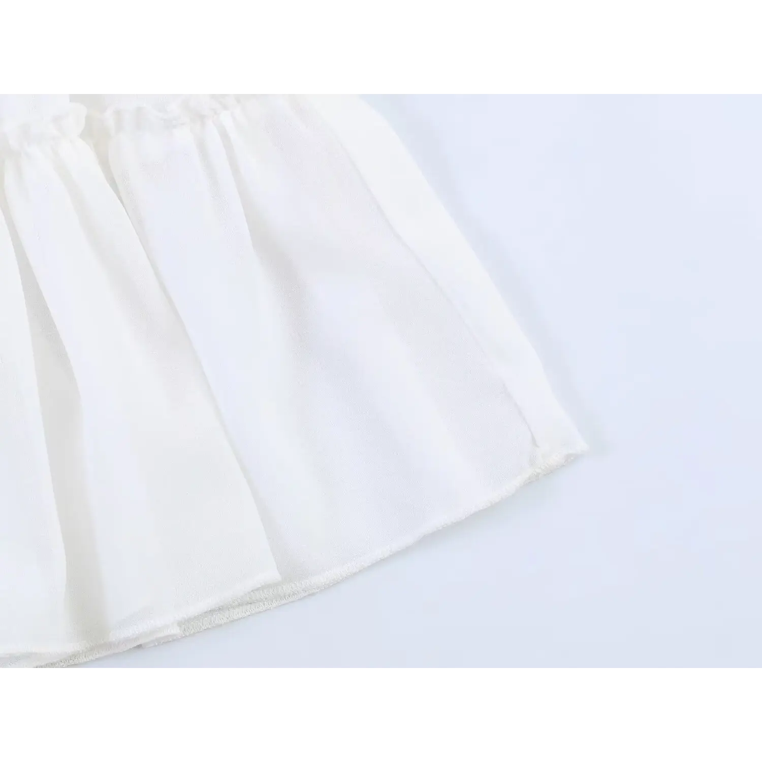 Flat close-up of single chiffon ruffle layer, showing lightweight flowy drape and fine hem stitching