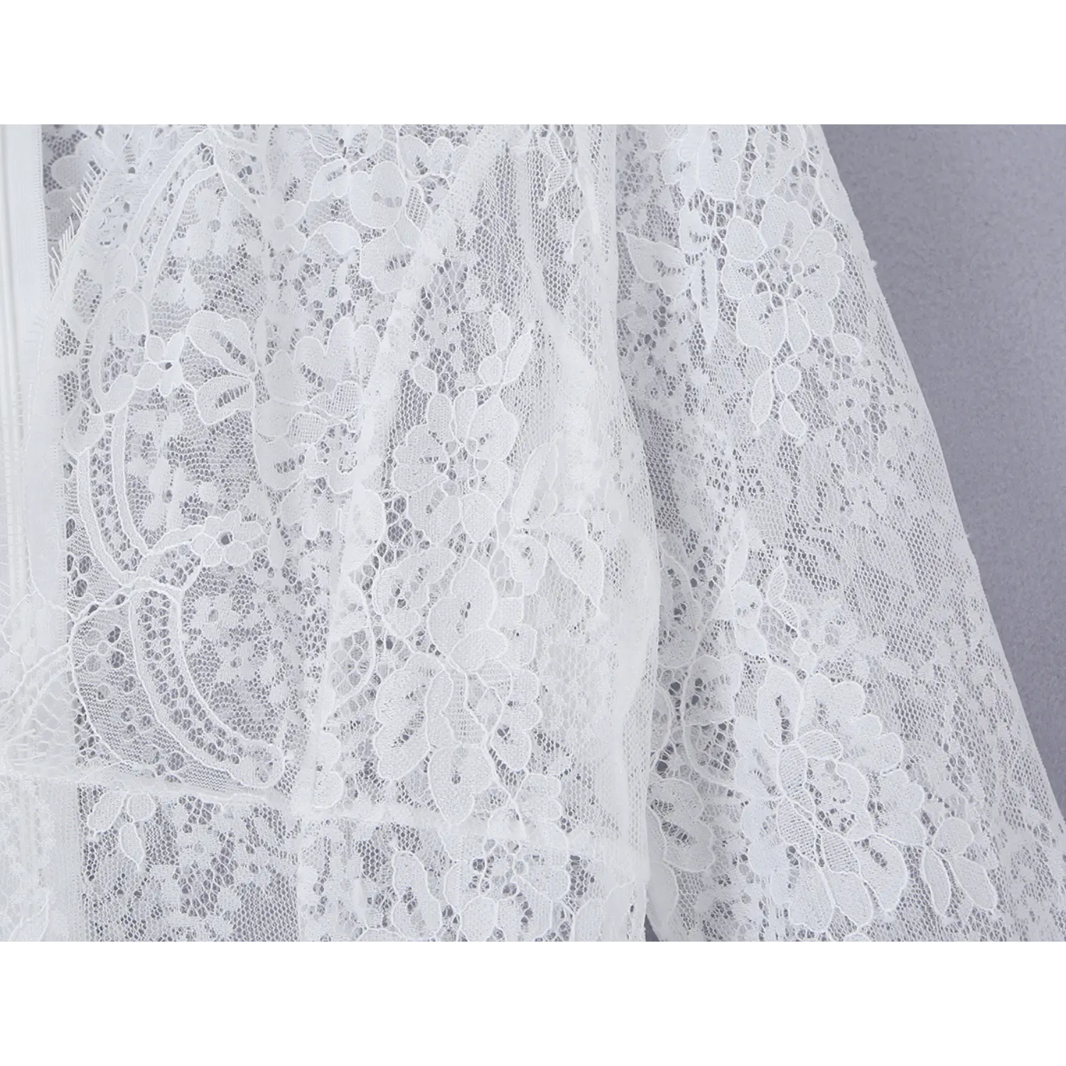Macro close‑up of intricate white floral lace fabric texture for floor‑length maxi dress