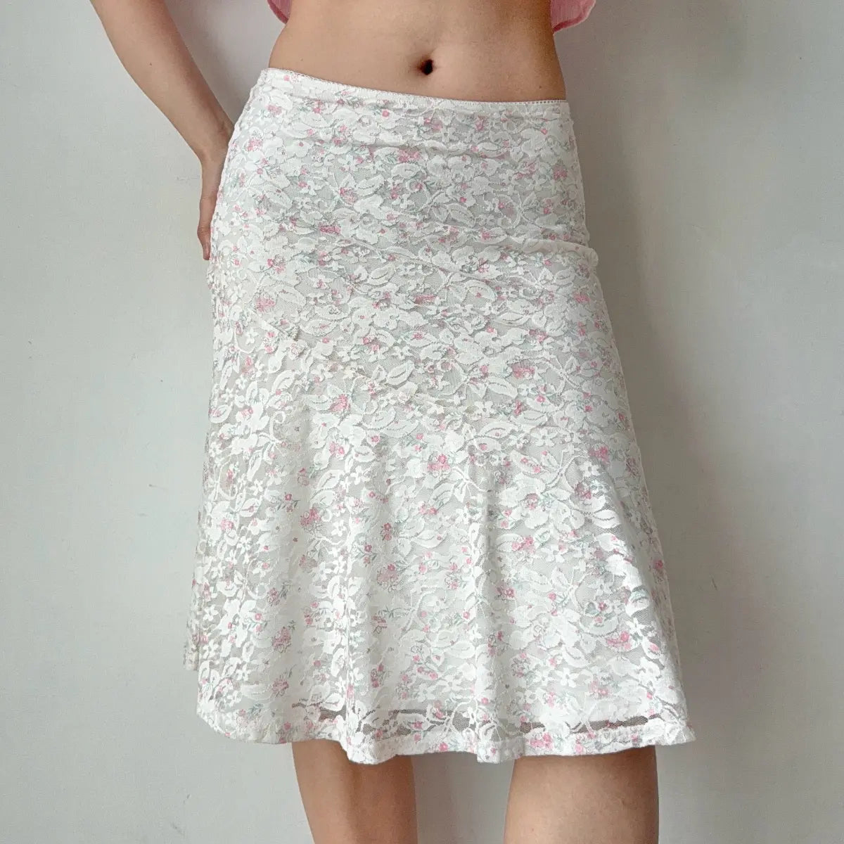 Slight side view of the white floral lace midi skirt, highlighting the flared hem.