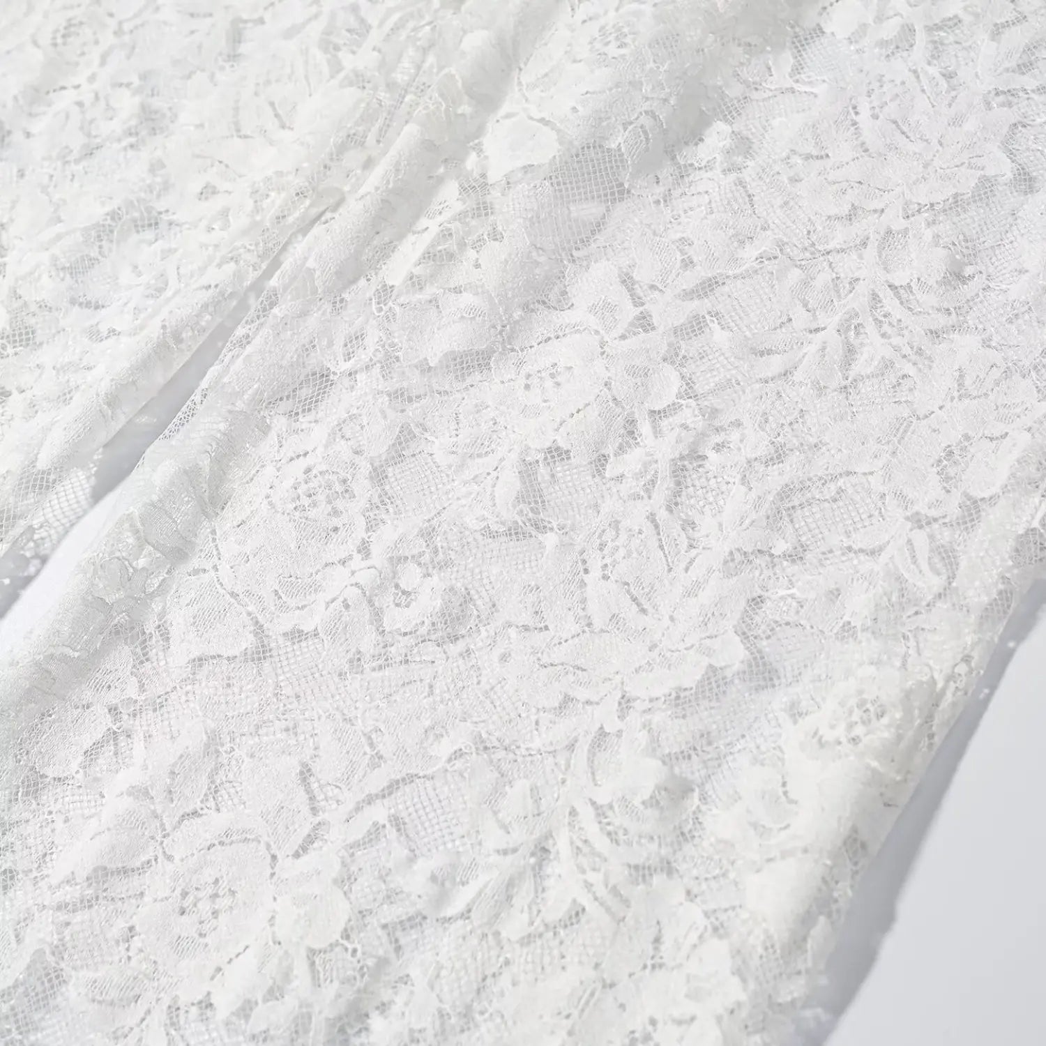 Close‑up full leg rose floral lace texture of white sheer wide leg pants