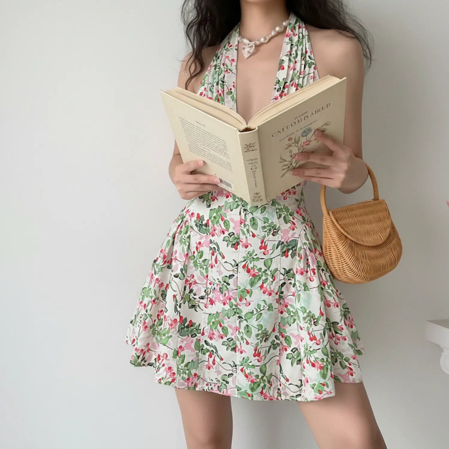 Front lifestyle shot on model of white floral halter mini dress, V neck, fitted waist, ruffle flared skirt, summer romantic sundress