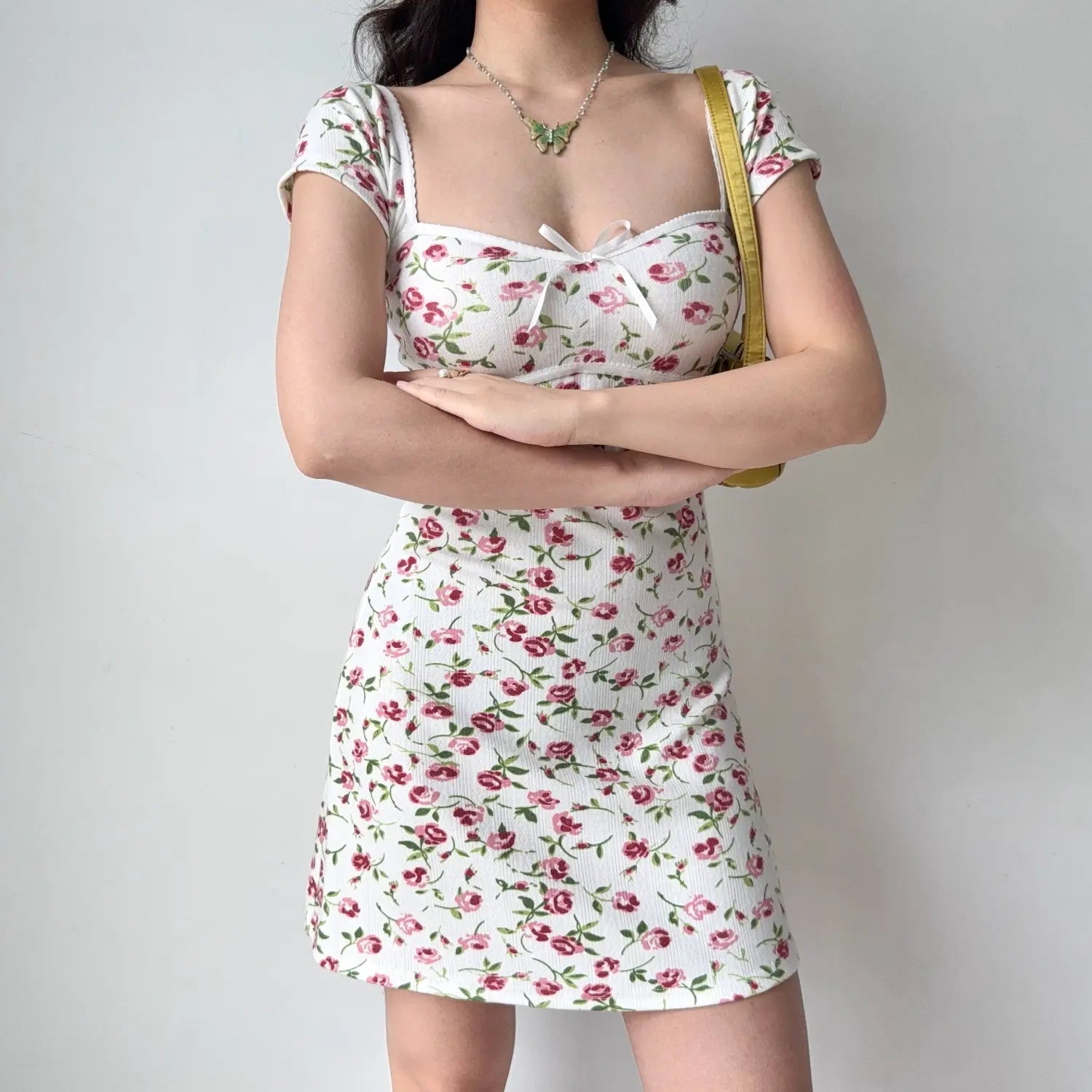 Front lifestyle shot on model of rose floral ribbed mini dress, scallop trim neck edge, front bow, slim everyday short dress