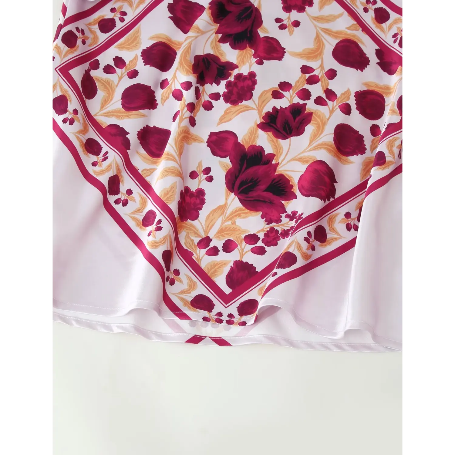 Close‑up of mermaid hem on white satin halter maxi dress, burgundy bandana floral print, satin fabric hem detail