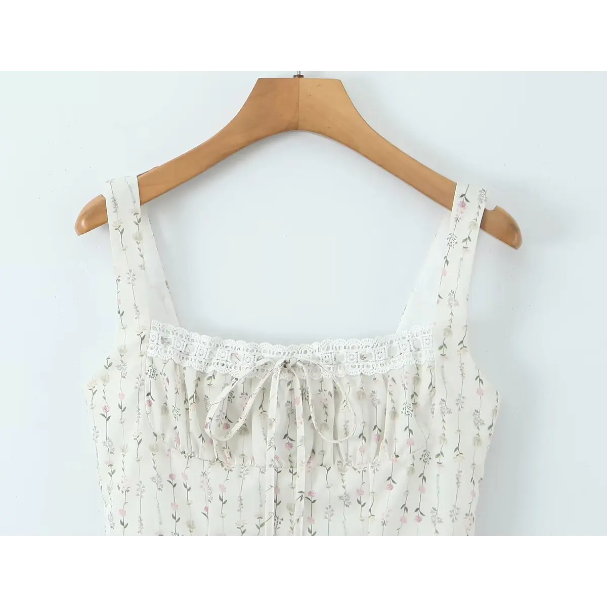 Close-up of the square neckline, shoulder straps, and front tie detail on the white floral cami dress