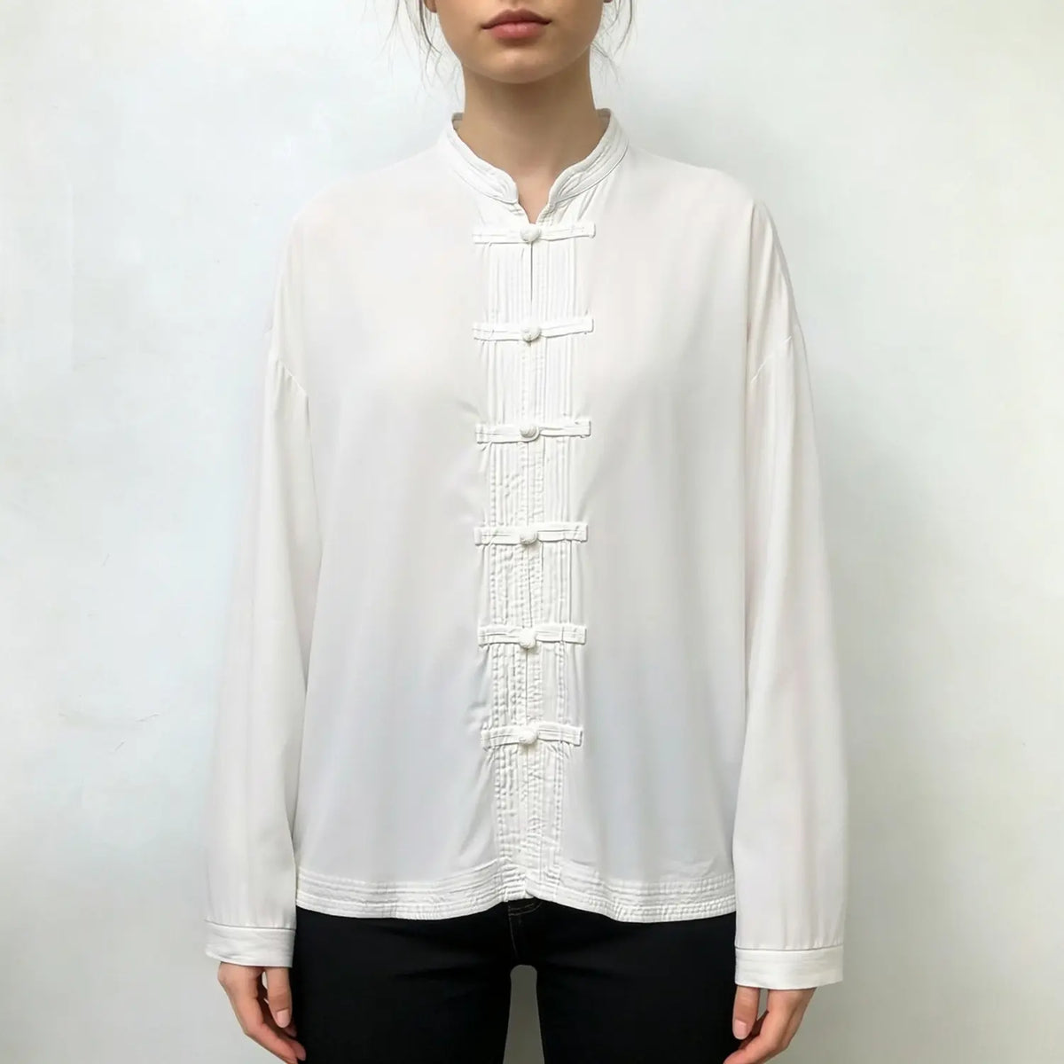 Model wearing white mandarin collar frog button shirt with black trousers