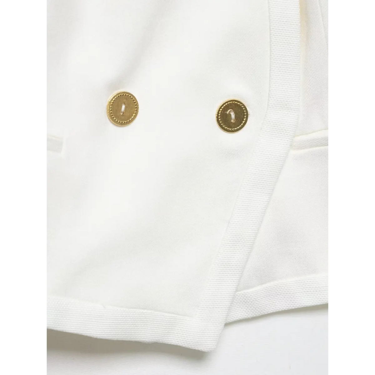 Close-up of gold metal buttons and asymmetric placket