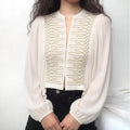 Model wearing white cropped blouse with gold cord embroidery, voluminous bishop long sleeves, casual outfit