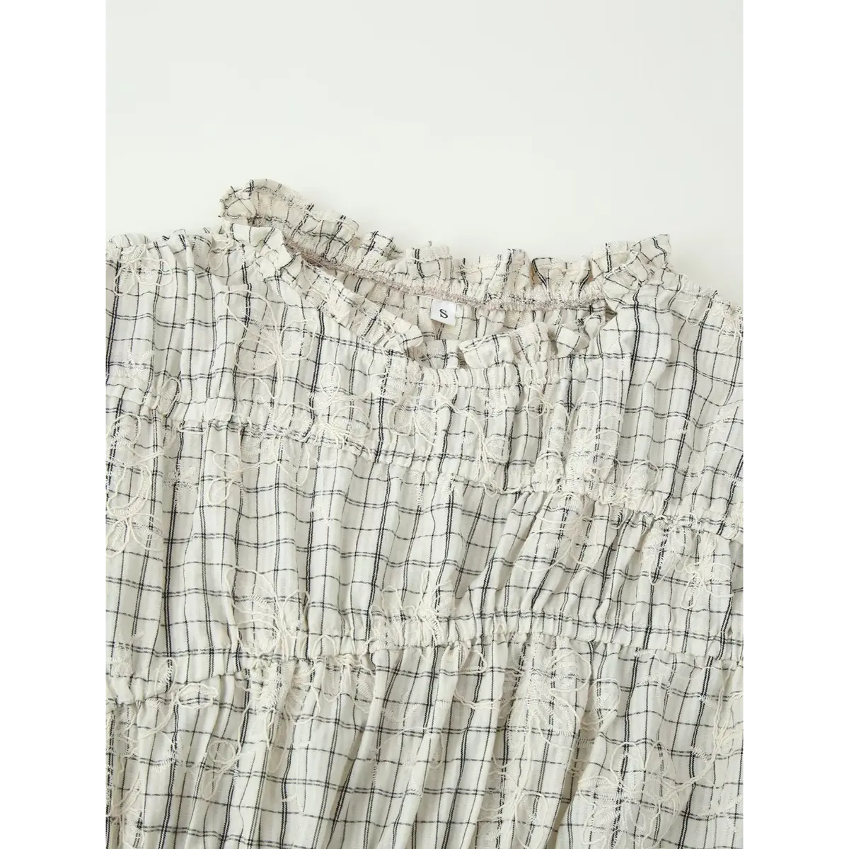 Back view of the white grid embroidered top, showing the ruffled high neck, tiered construction, and size label