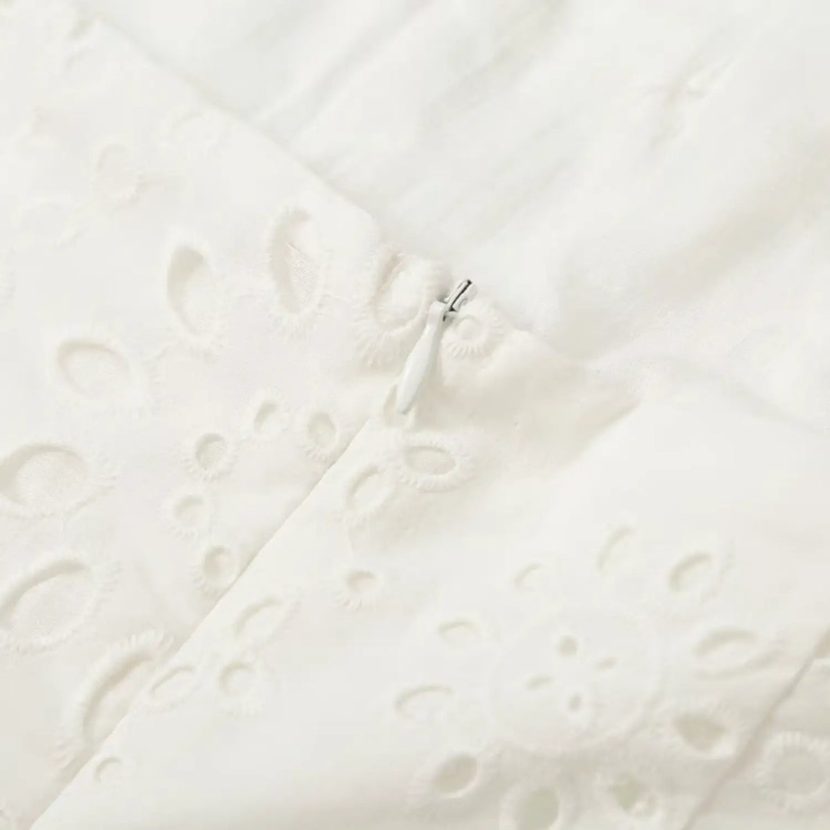 Close-up of back zipper on white eyelet embroidered dress