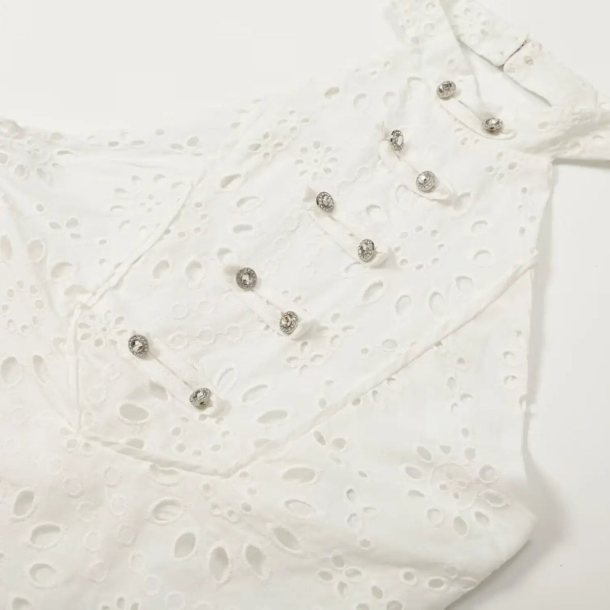Close-up of bodice with rhinestone button placket on white eyelet dress
