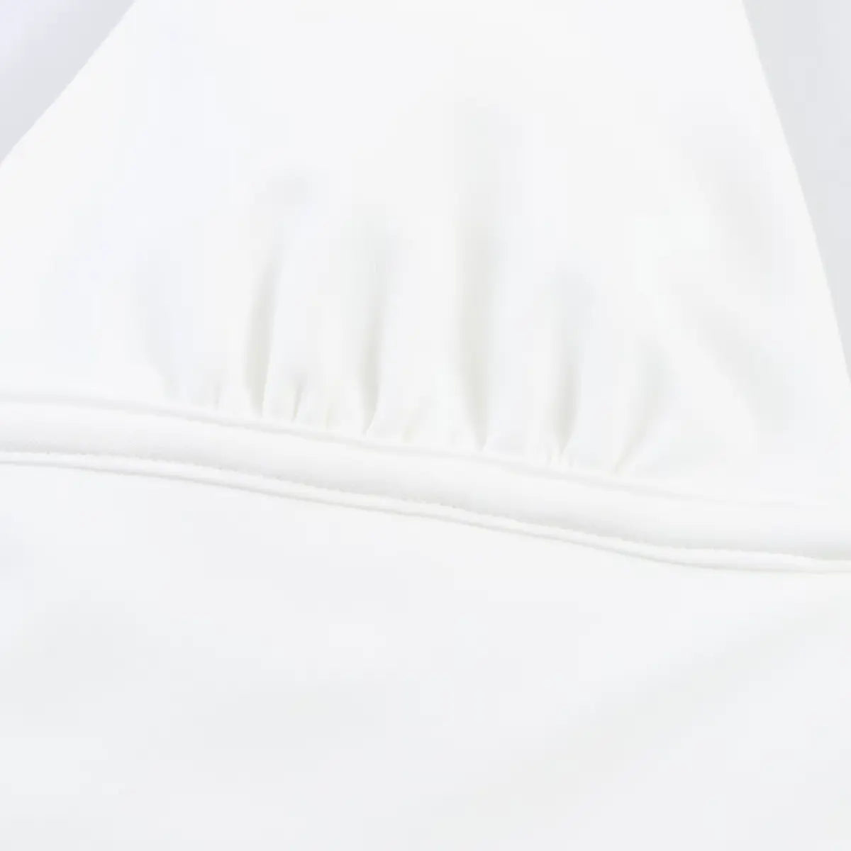 Close-up of the gathered bust area on white halter dress, showing soft fabric texture and stitching.