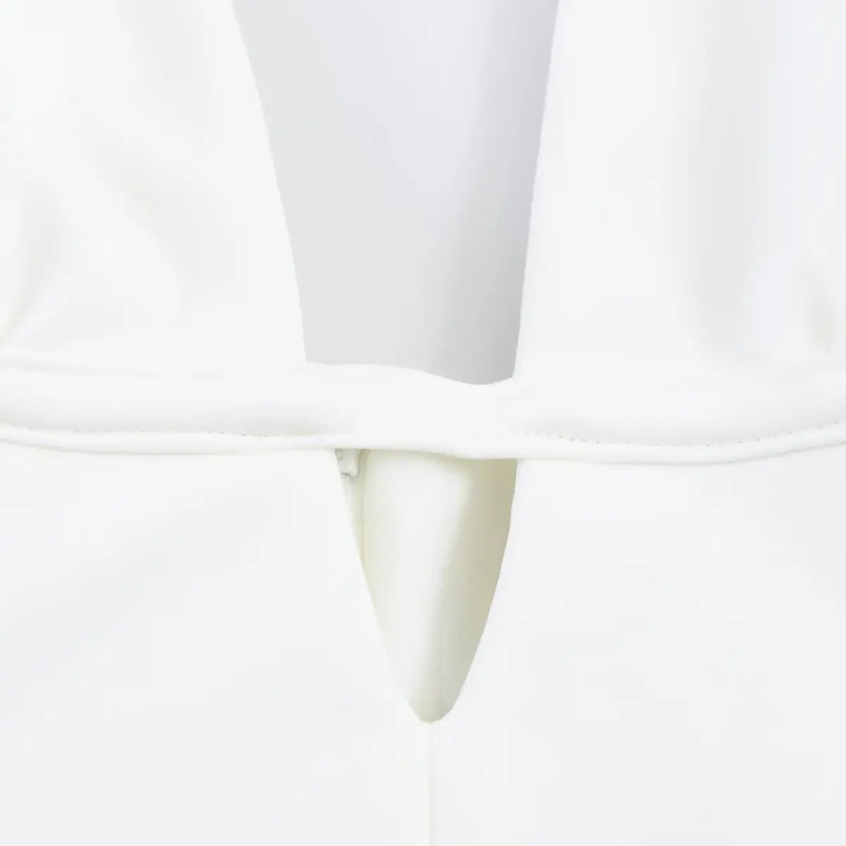 Close-up of the V-neck cutout detail on white halter dress, showing gathered bust stitching.