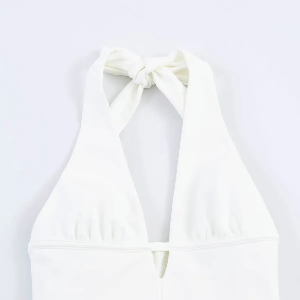 Top view of the halter neckline on white dress, showing the back tie knot and open neck design.