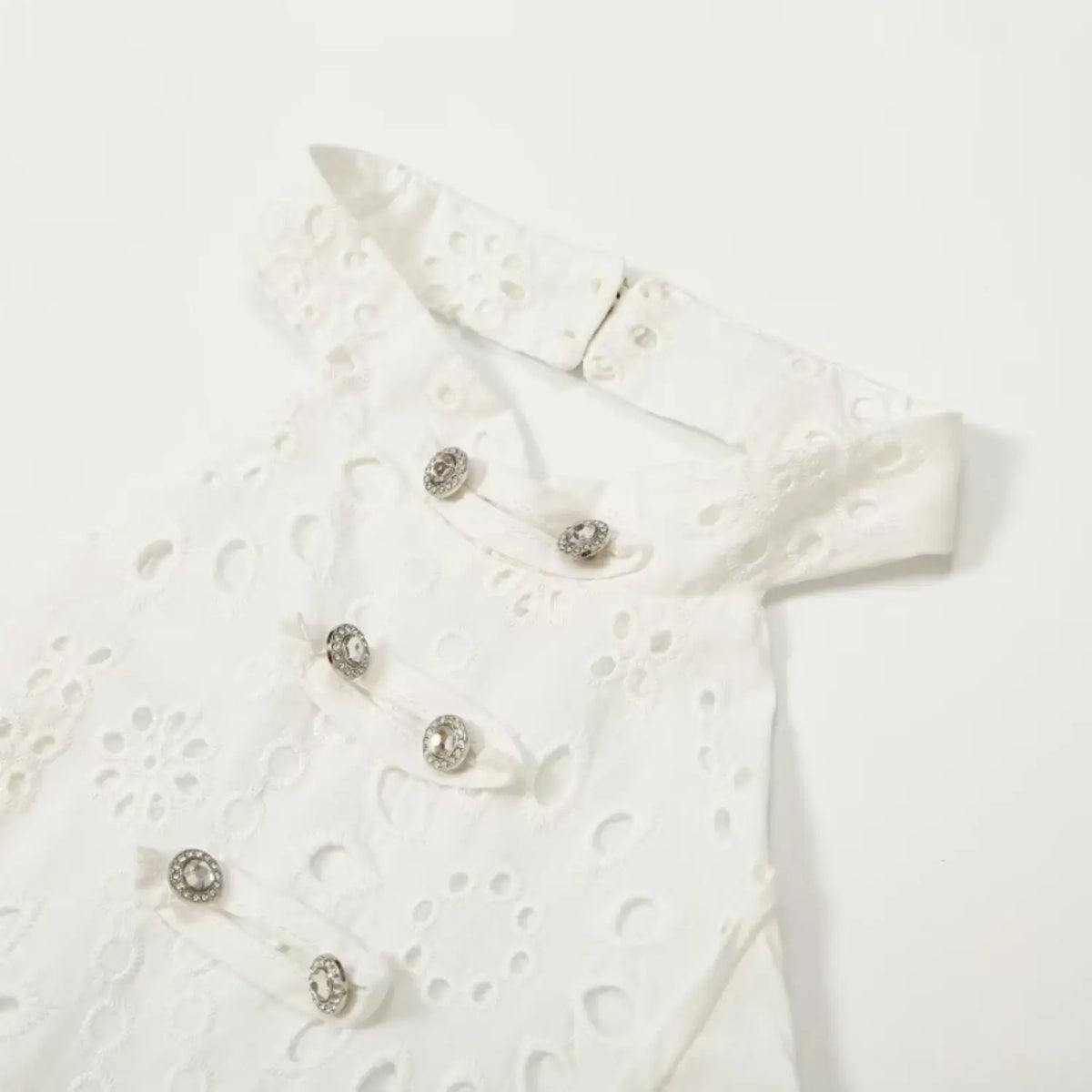 Close-up of halter neckline and rhinestone buttons on white eyelet dress