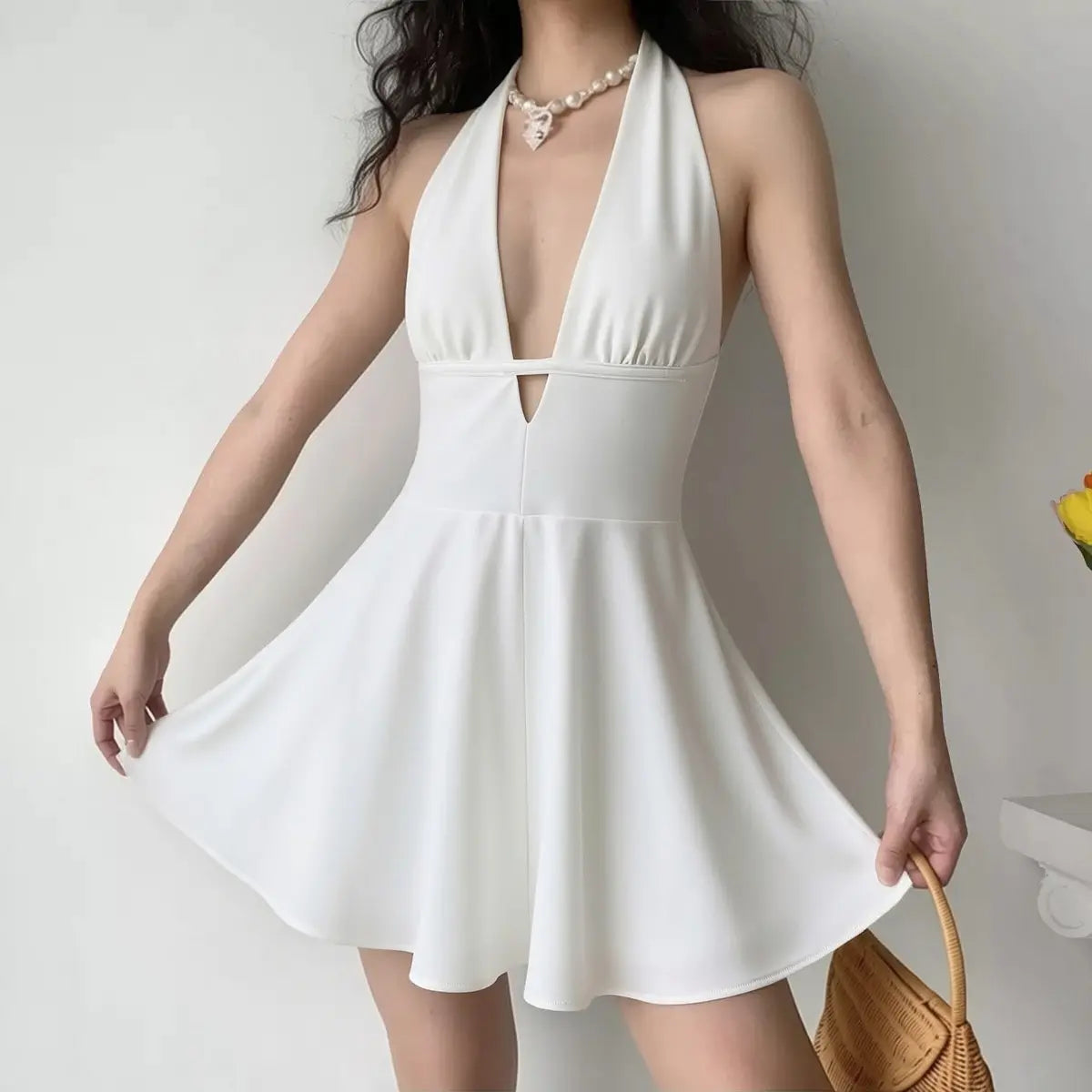 Model wearing white halter mini dress with a rattan bag, showing the fitted silhouette for casual summer wear.