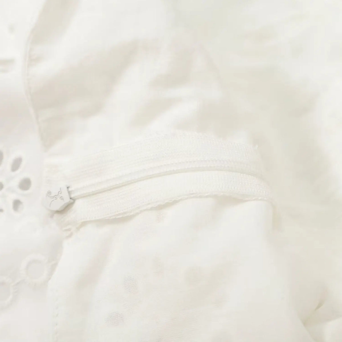 Close-up of white zipper pull and tape on back of dress