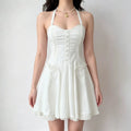 Model wearing a white halter-neck corset-style mini dress with ruffled front details, buttons, and pleated hem accents.