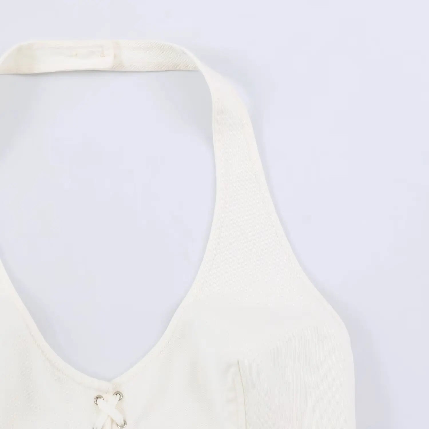 Macro shot of slim halter neck strap and deep v neck twill fabric of white bodycon dress