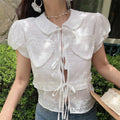 Front view of the white embroidered blouse with heart-shaped pockets and tie closures.