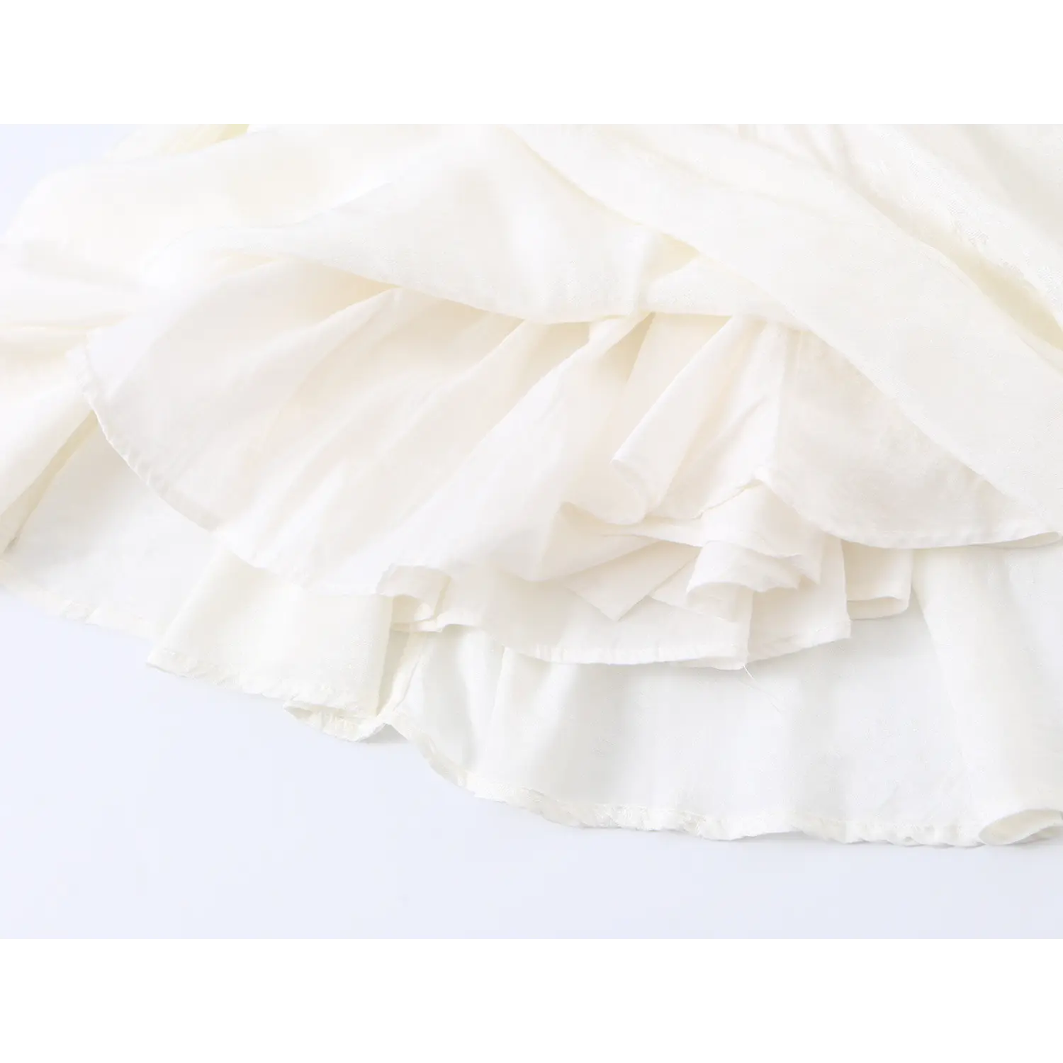 Multi-layer flowy ruffle skirt hem close up, lightweight sheer white floral jacquard fabric stitching