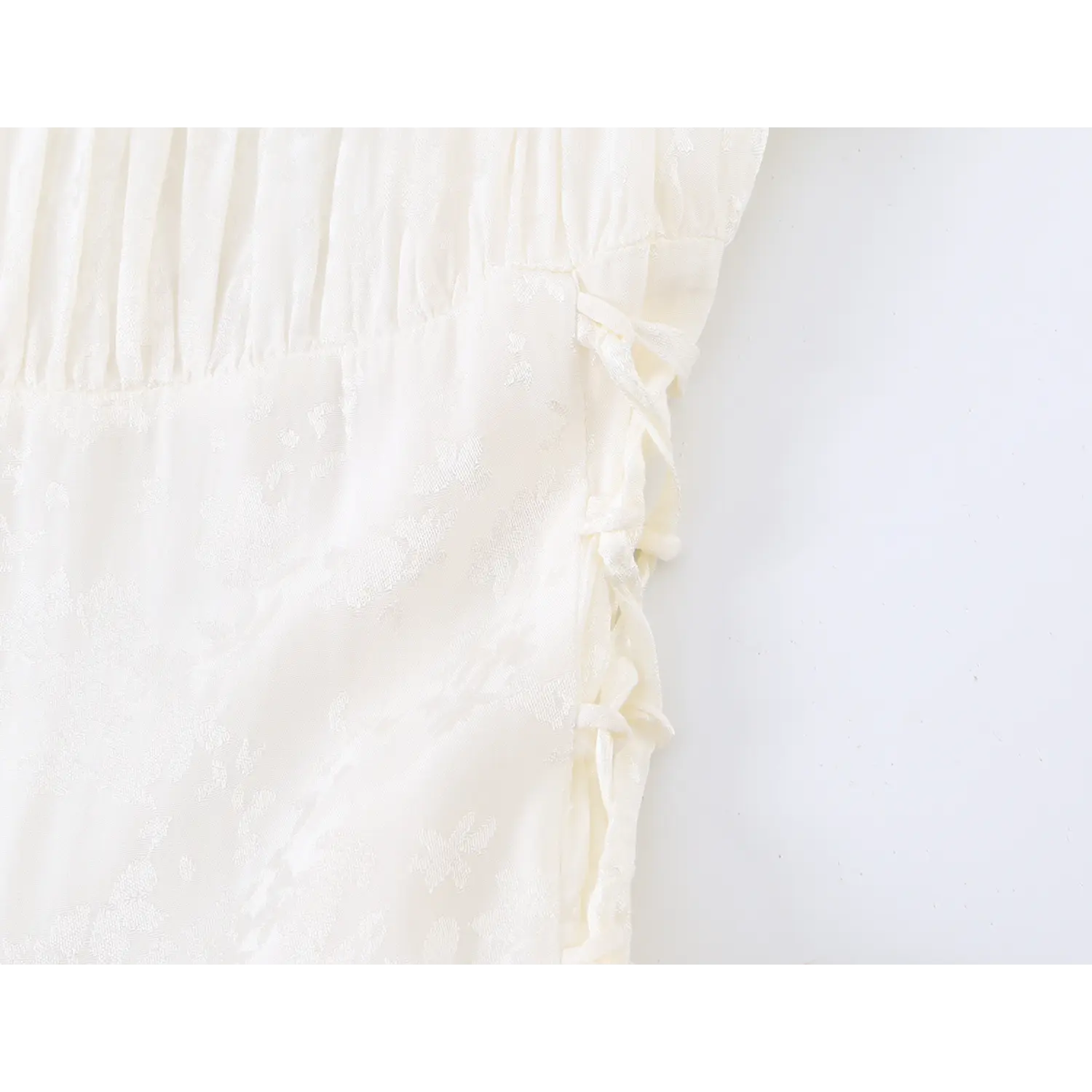 Side corset lace up tie close up, matching white ribbon drawstring on subtle floral jacquard dress bodice