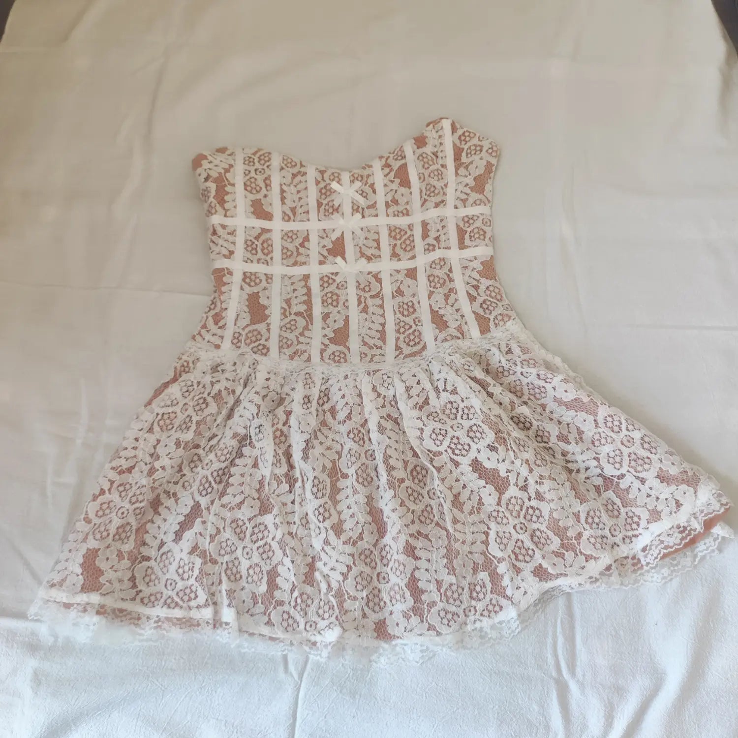 Flat lay front view, white floral lace strapless corset mini dress with satin ribbon bows and flared skirt