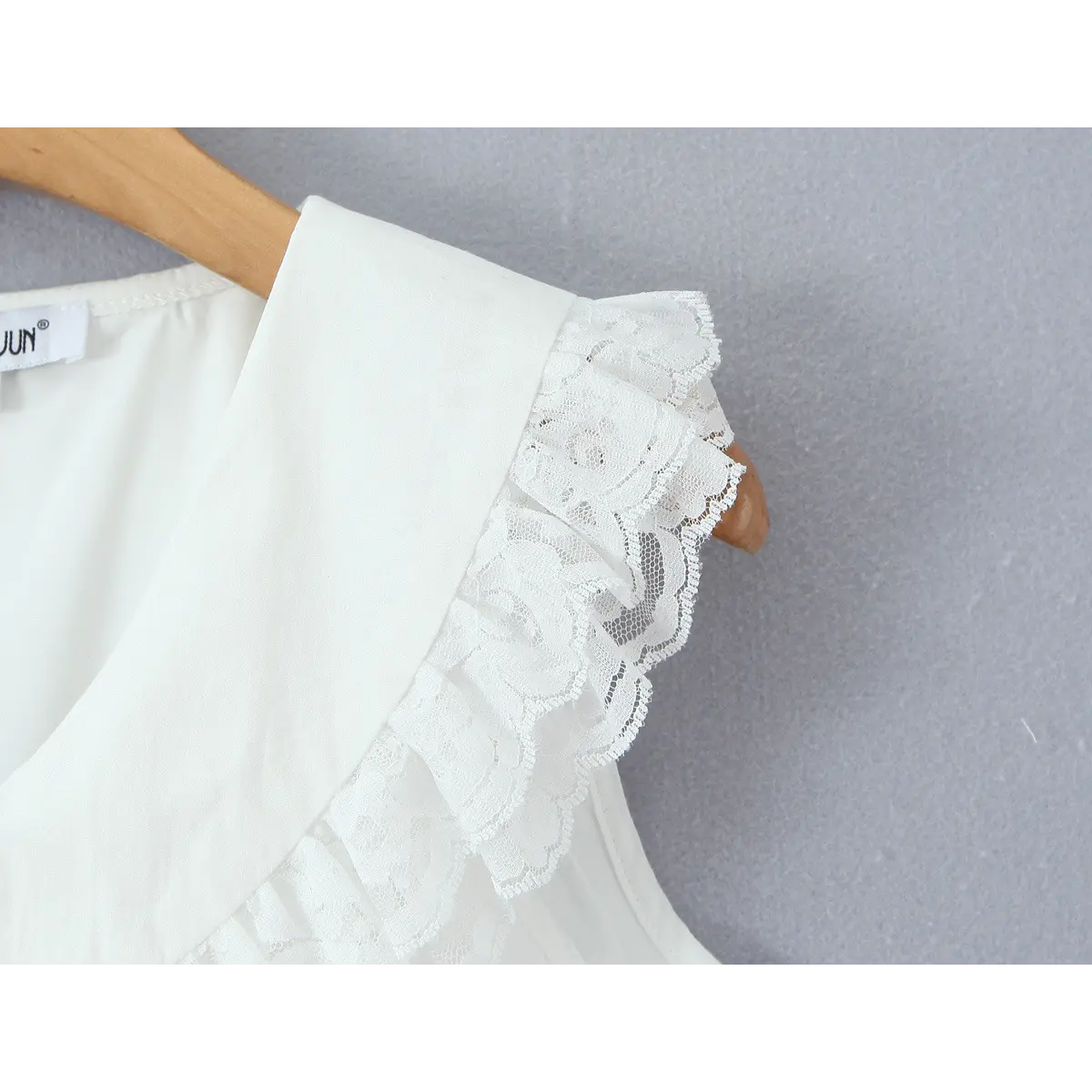 Close-up of the shoulder area, showing the layered lace ruffles and Peter Pan collar.