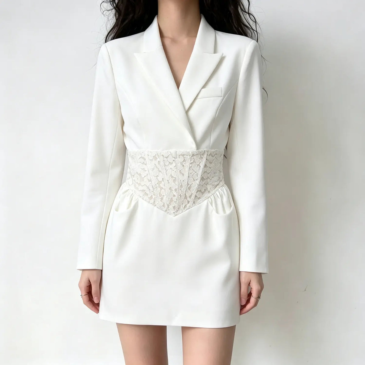 Model wearing white long sleeve blazer mini dress, notched lapel, floral lace corset waist with side pockets