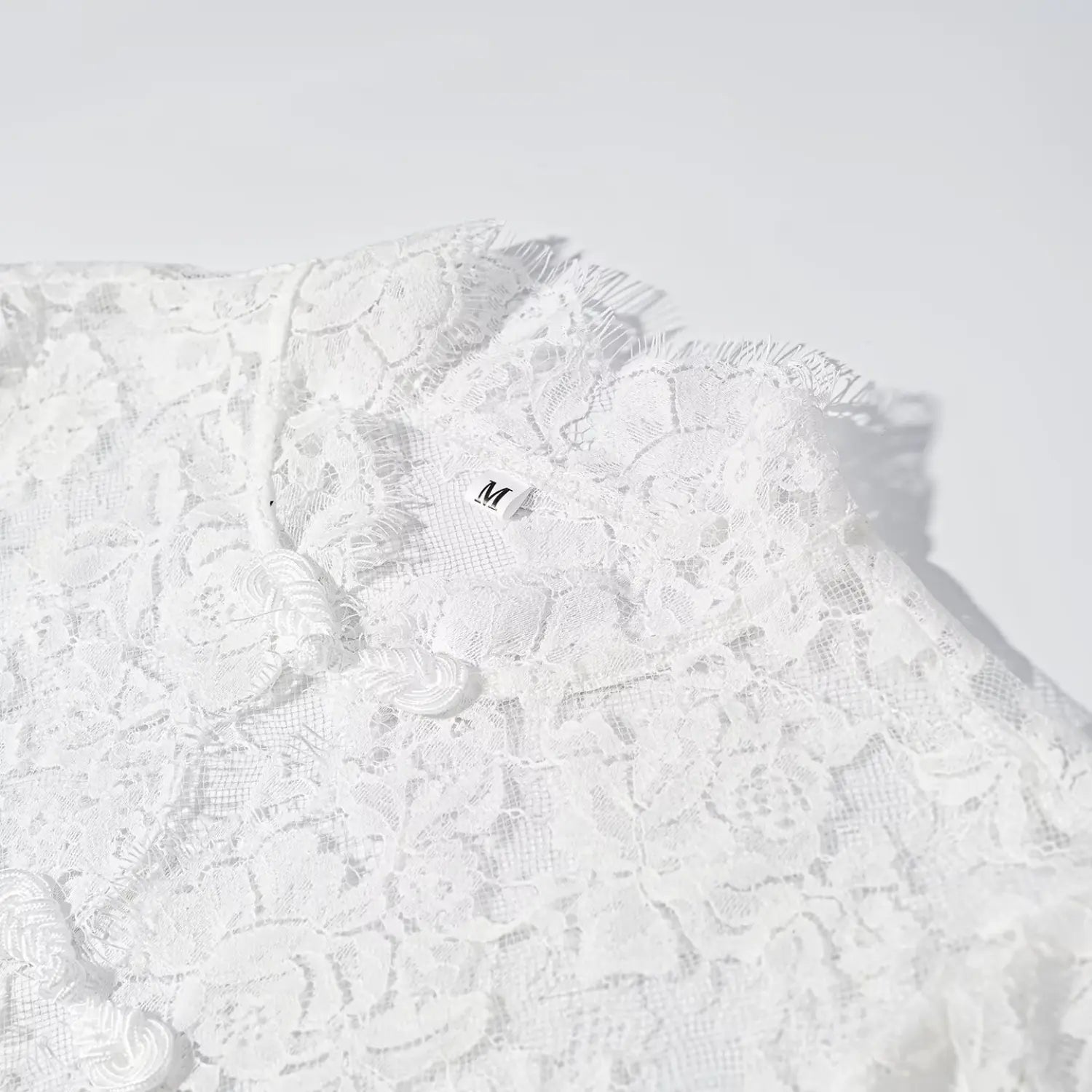 Close‑up shot stand collar, frog buttons and inner size tag white lace maxi dress