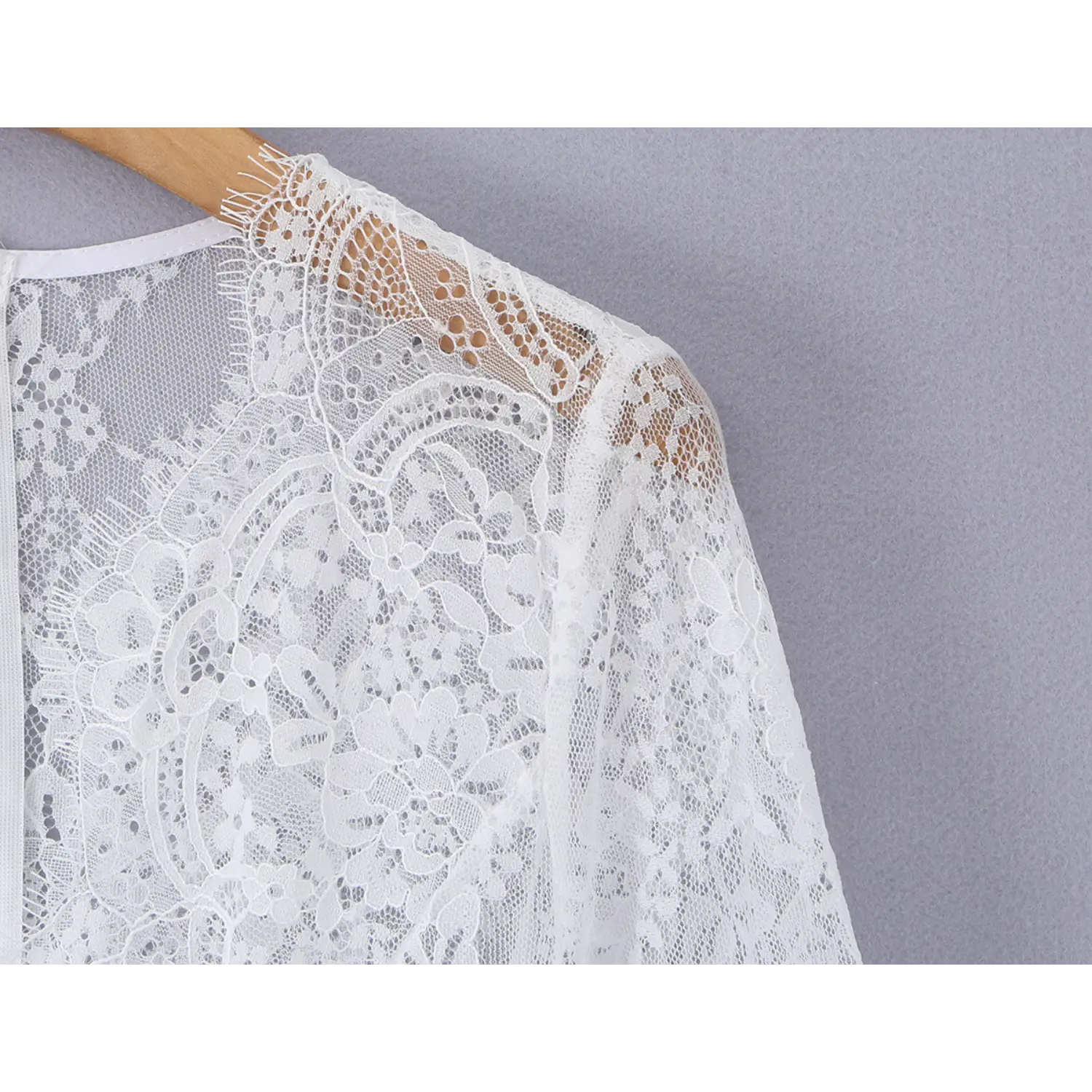 Close‑up of intricate floral lace craftsmanship on shoulder and neckline of white long sleeve mini dress