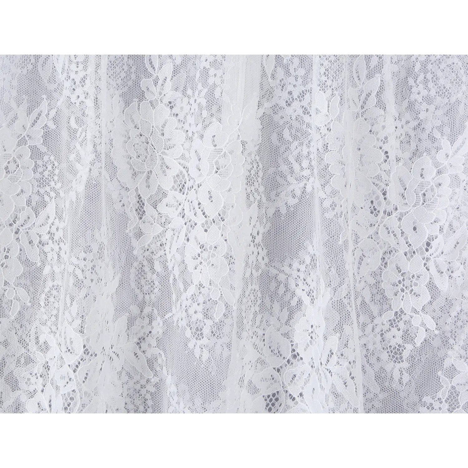 Close‑up of scalloped floral lace fabric texture on skirt section of white mini dress