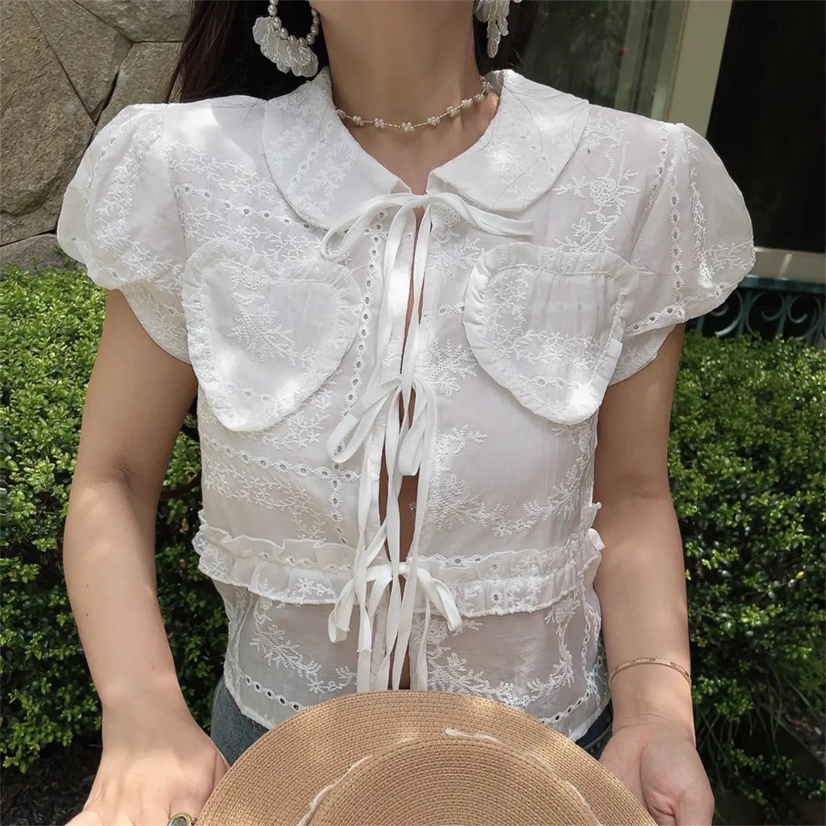 The complete outfit of the white embroidered blouse paired with jeans and accessories.