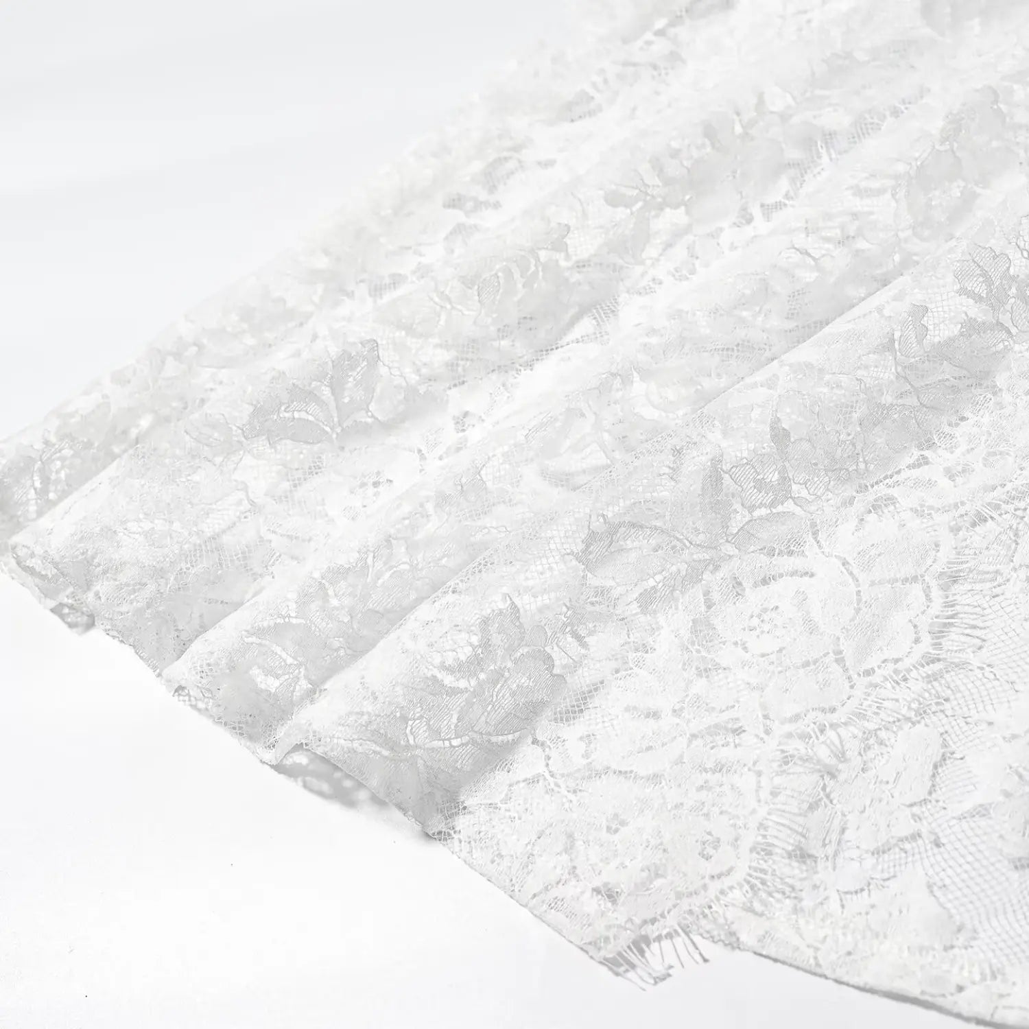 Close‑up folded hem fringe edge of white rose floral sheer lace fabric