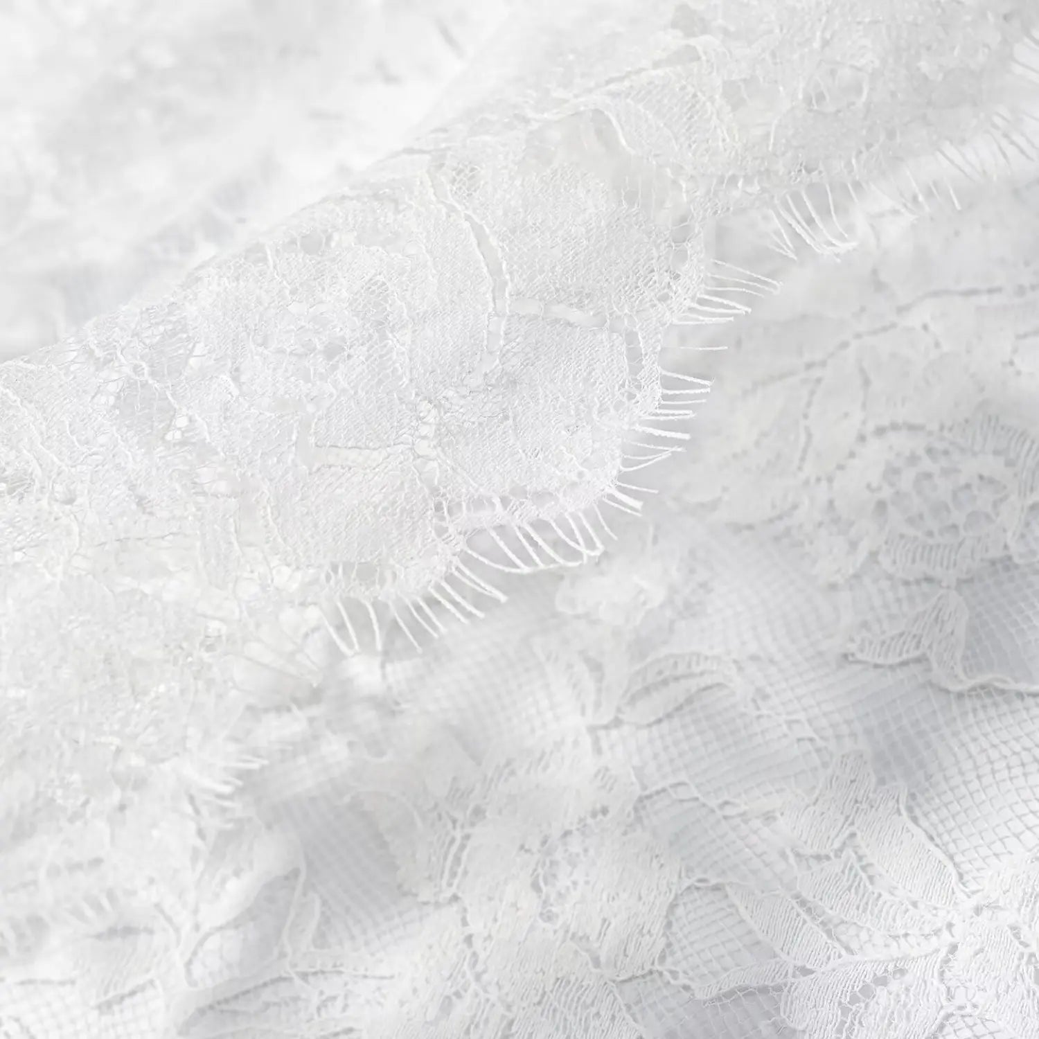 Extreme close‑up scalloped fringe trim detail on white floral lace material