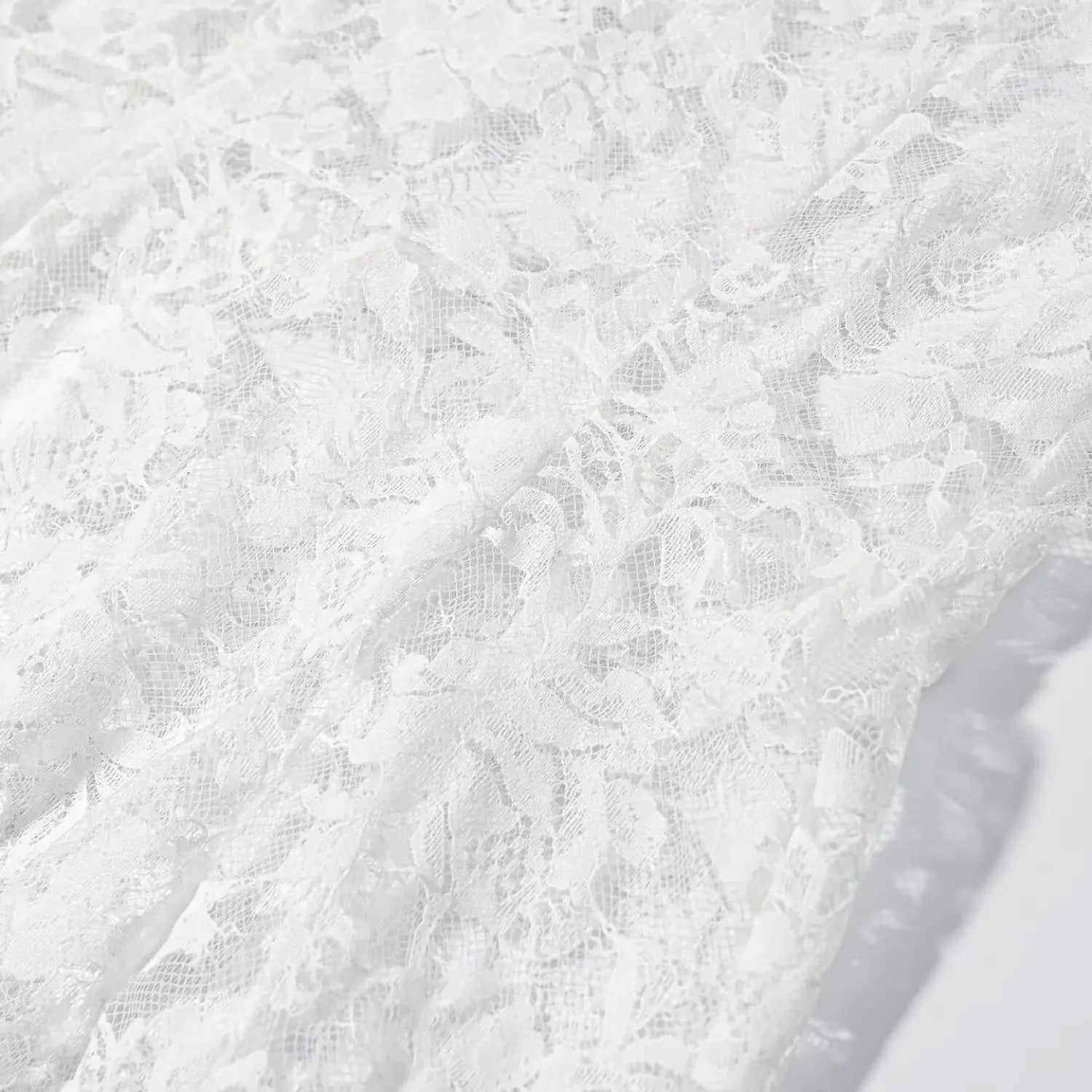 Close‑up soft folded wrinkle texture of white floral sheer lace fabric