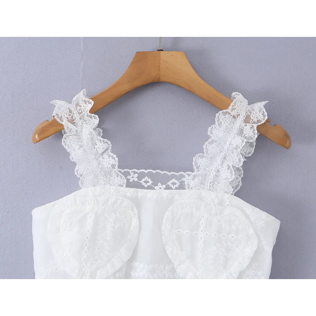 Close-up of the front neckline, featuring the scalloped lace trim and heart embroidery.
