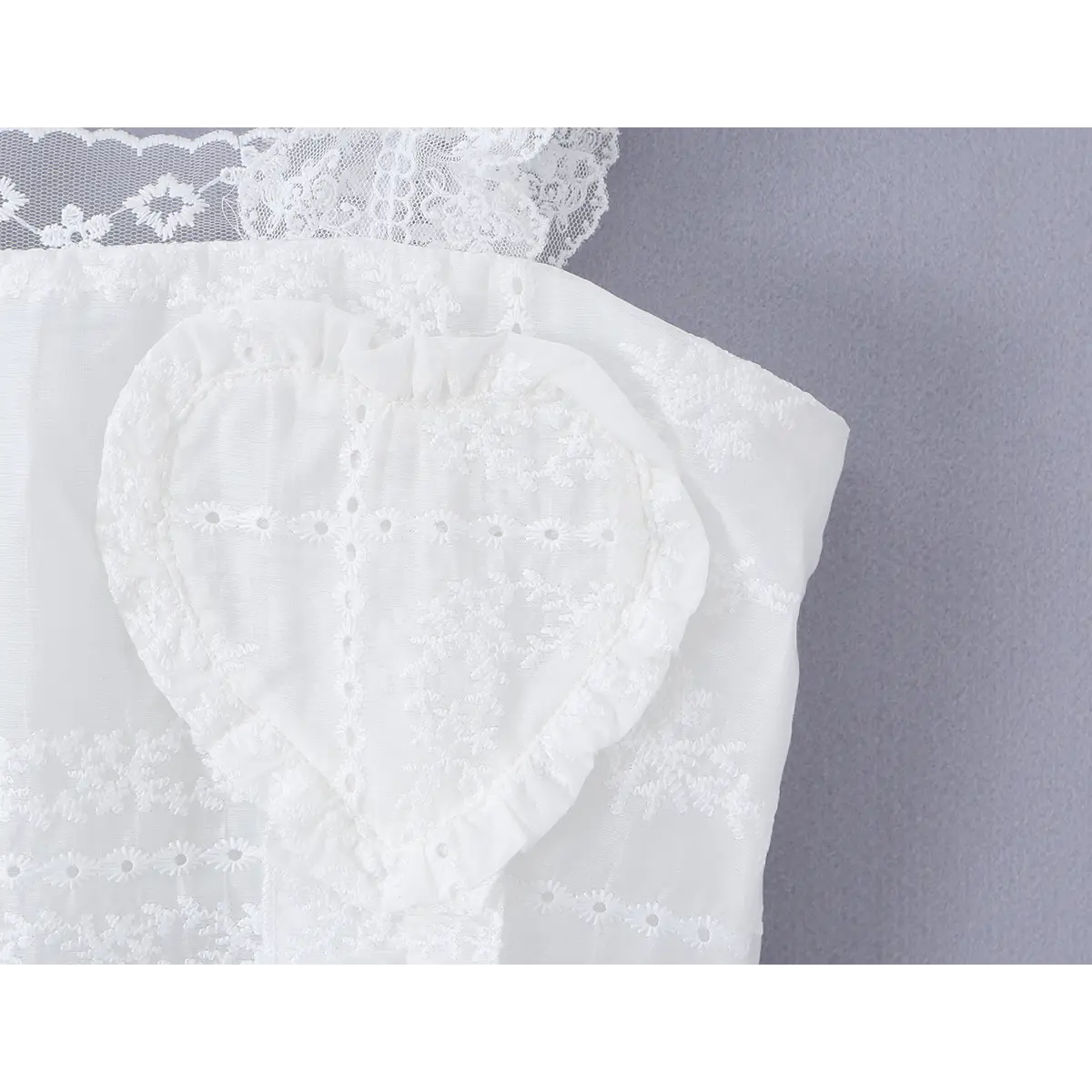  Close-up of the heart-shaped embroidered bust detail, showing the floral stitching and ruffled trim.