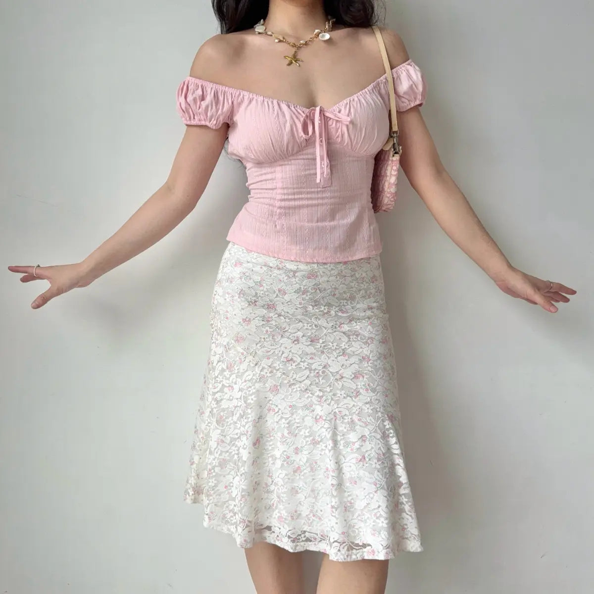 Full outfit view of the white floral lace midi skirt paired with a pink off-the-shoulder top.