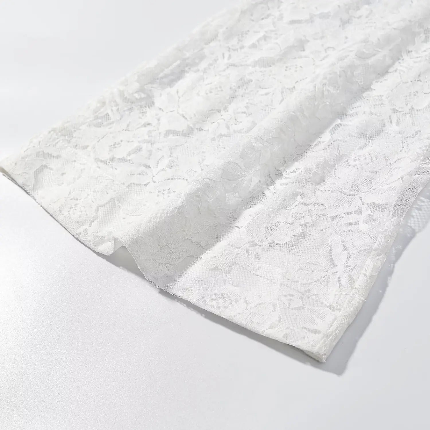 Flat lay view pant leg hem scalloped fringe edge detail for white floral lace trousers