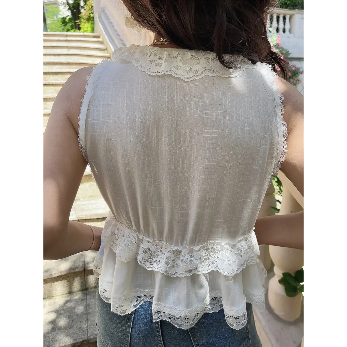 Back view of the white lace-trimmed peplum vest, showing the sheer grid-pattern fabric, scalloped lace trims, and tiered peplum hem