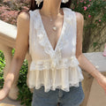 Front view of the white lace-trimmed peplum vest, featuring a deep V-neck, ruffled lace trim, and front drawstring tie, worn with denim shorts