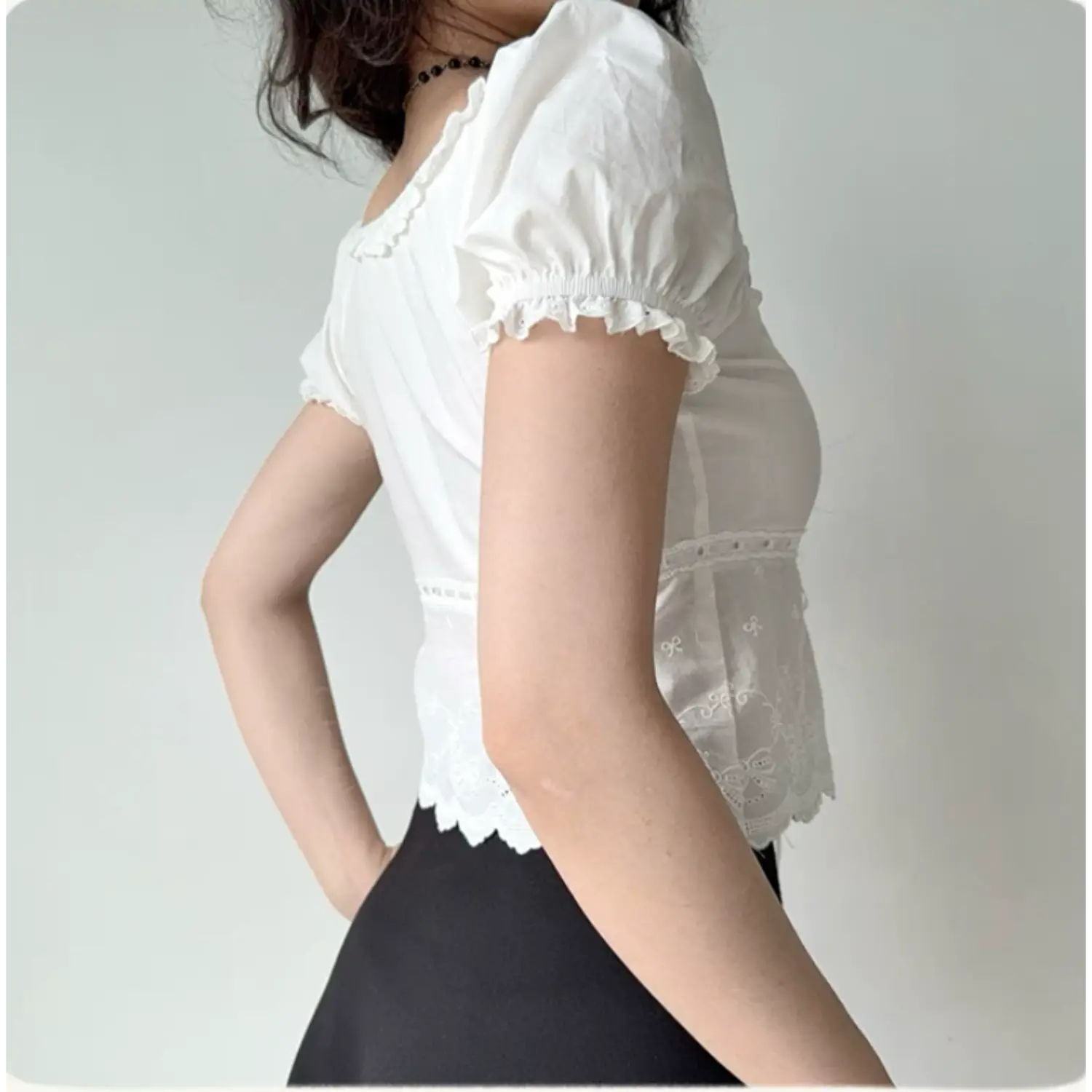 Lifestyle back shot of a woman wearing a white lace-trimmed puff sleeve top